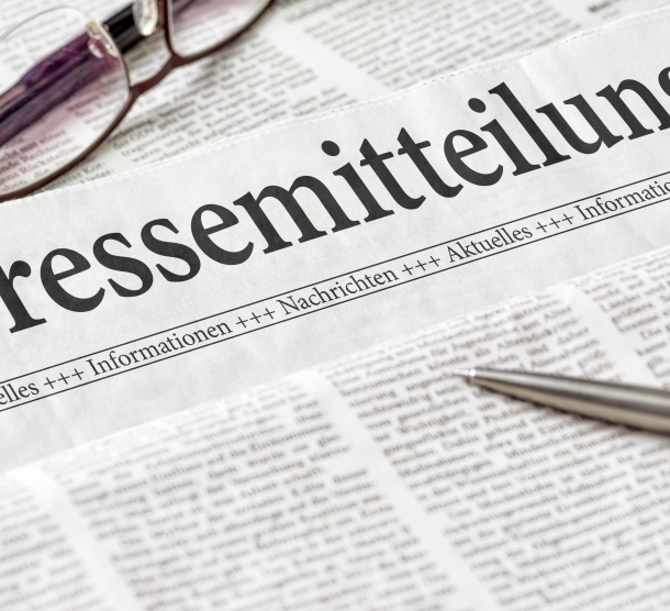 Zeitung mit der Überschrift Pressemitteilung. Eine Brille und ein Kugelschreiber liegen auf der Zeitung.