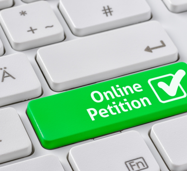 Ausschnitt eines Teil einer weißen Computer-Tastatur, bei der die Shift-Taste grün eingefärbt und mit dem Wort "Online-Petition" beschriftet ist.